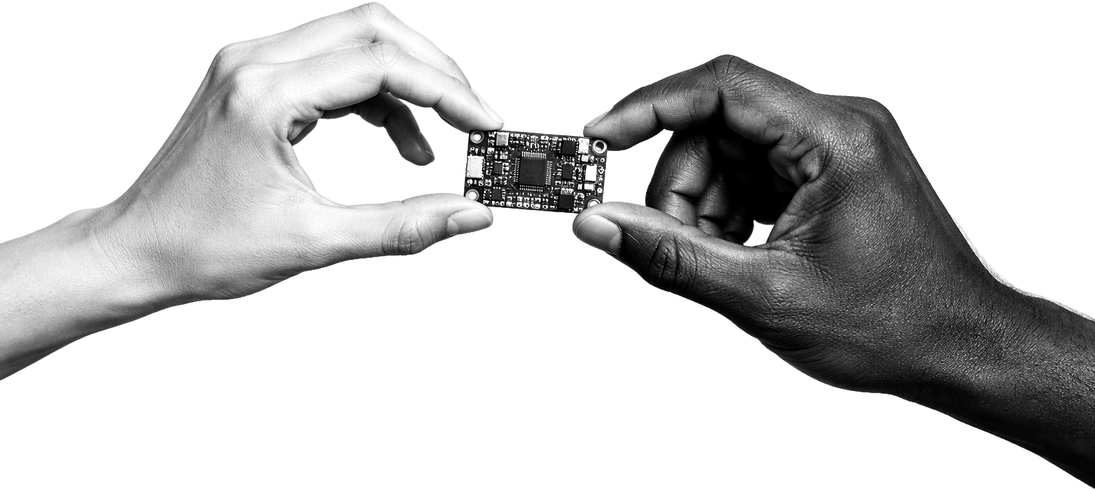Two hands from different people holding a small circuit board between them