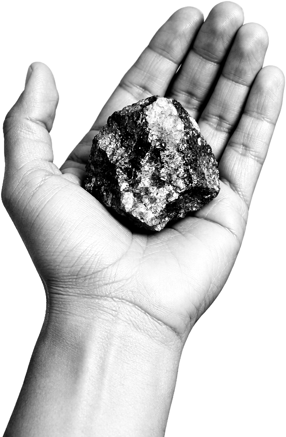 An open palm holding a chunk of raw mineral ore